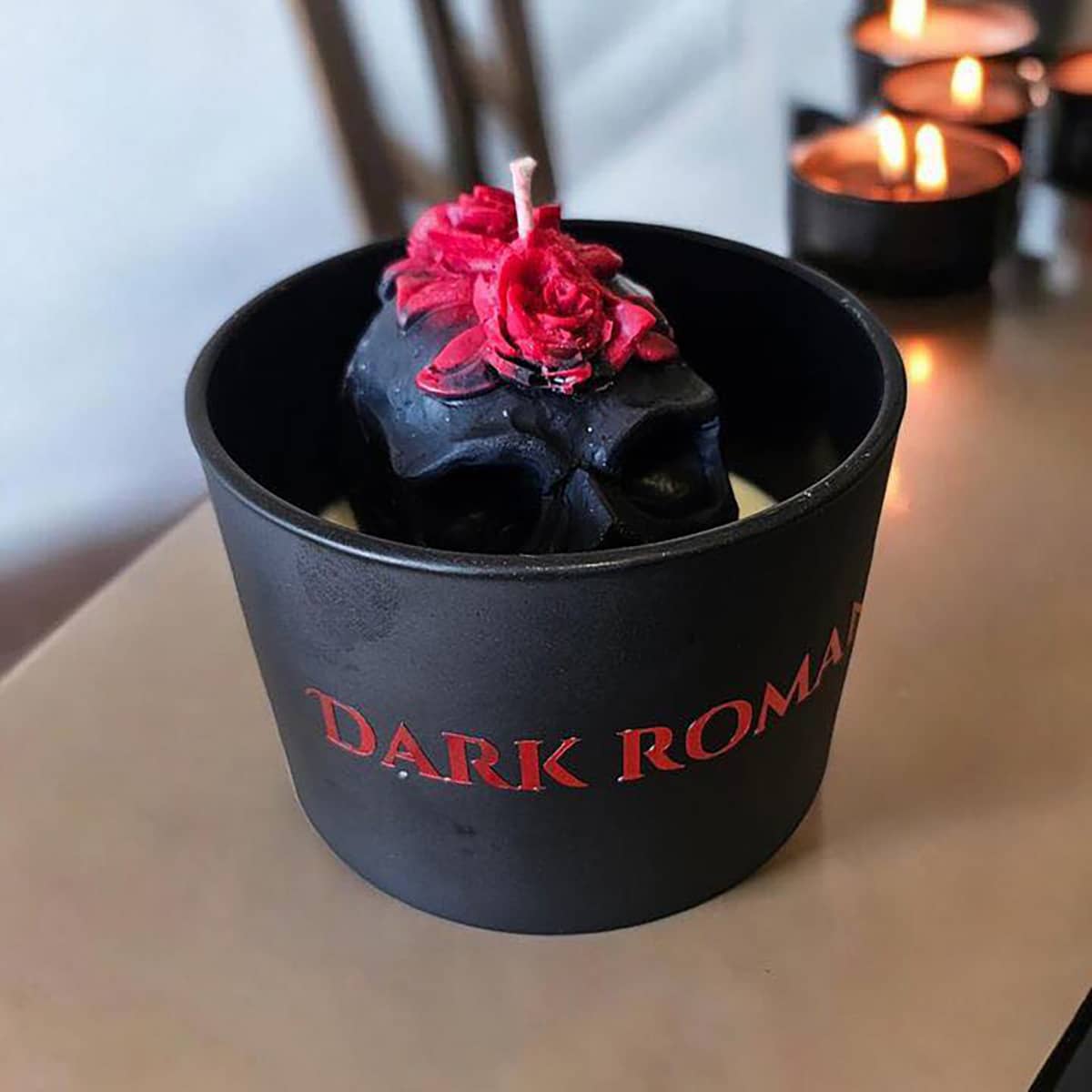 The Indie Realm Dark Romance Candle featuring red rose on black skull design on white wax in black jar