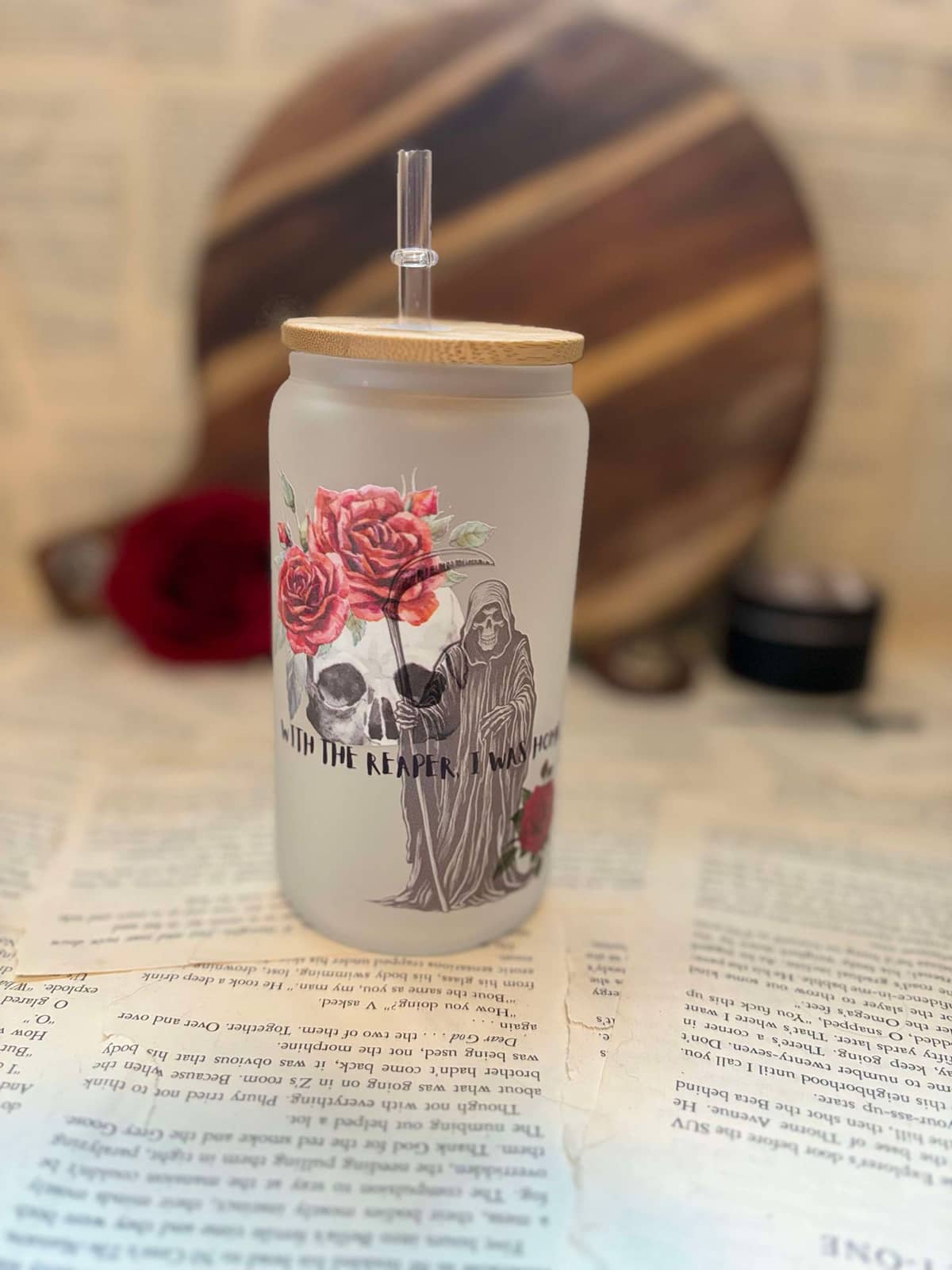 Jasmine Styles' Blooming in Death themed  frosted glass cup featuring red roses and grim reaper design with black graphic text on frosted glass, with wooden lid and clear straw