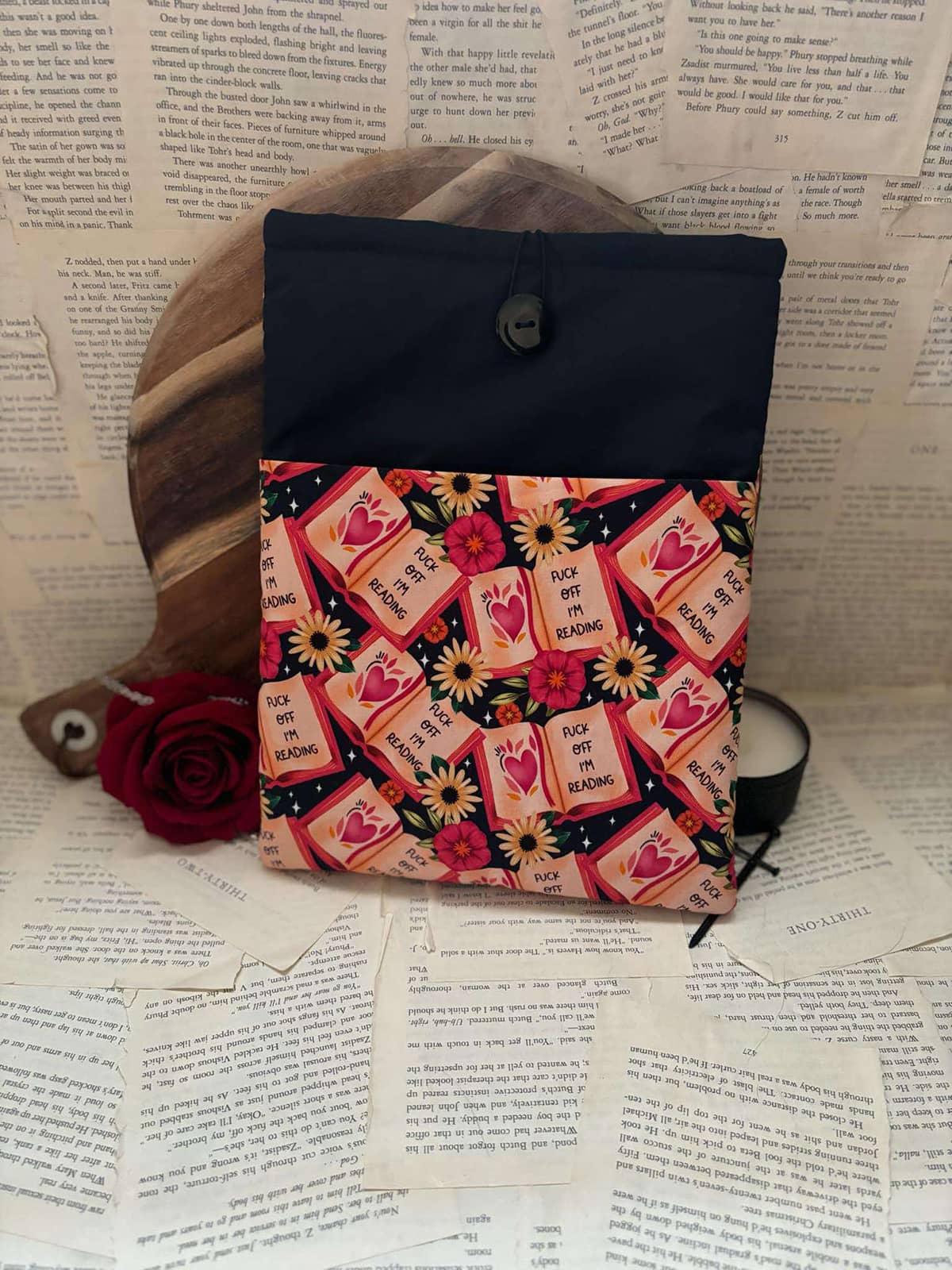 Large book sleeve featuring red books, poppies and sunflowers on black fabric with graphic text "Fuck off I'm reading"