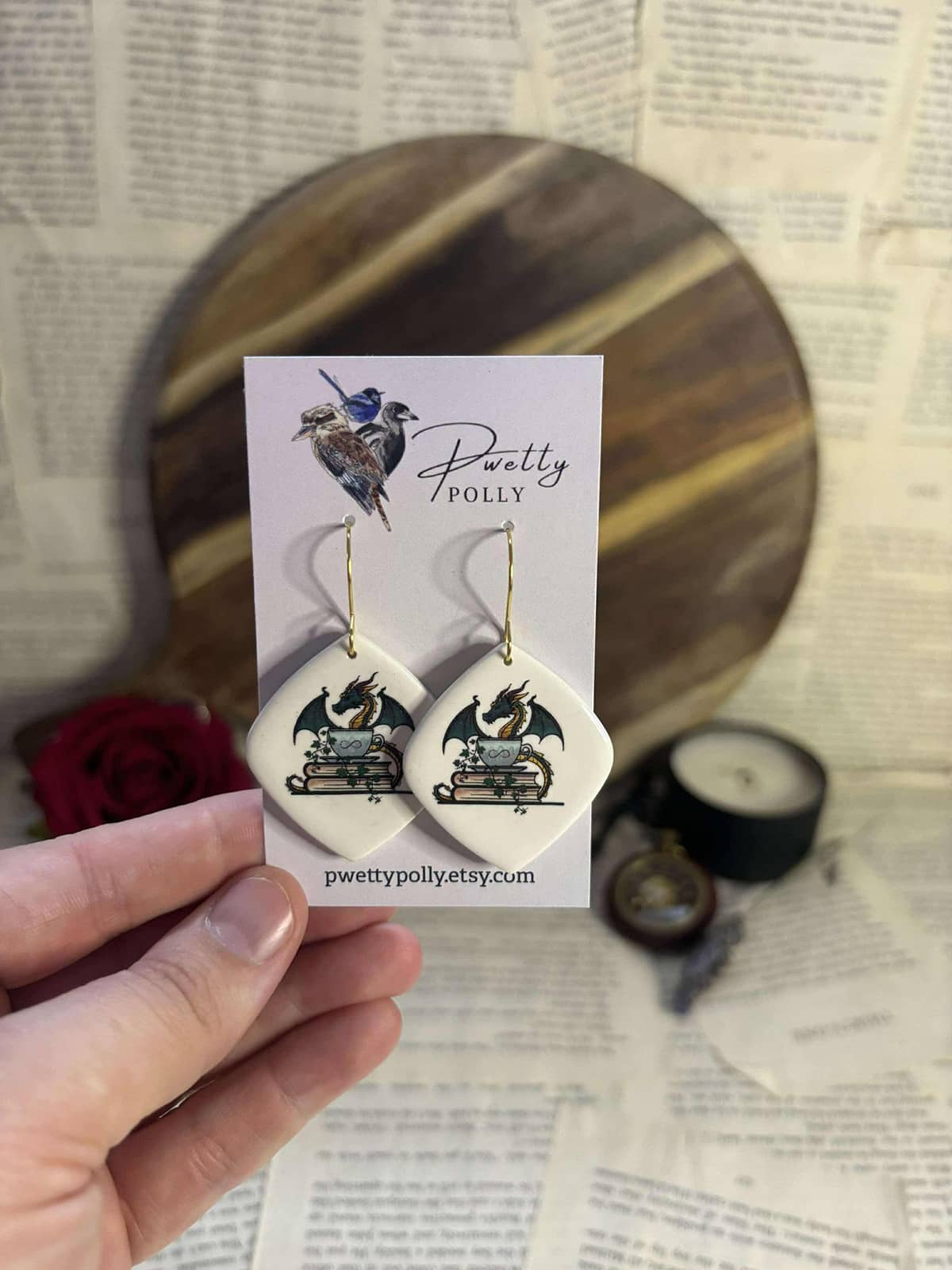 Gold hardware earrings with polymer clay design of The Indie Realm logo on white diamond background