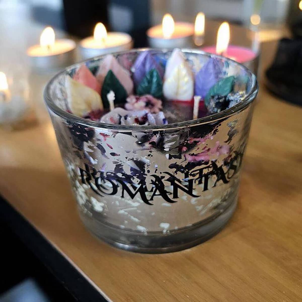 The Indie Realm Romantasy Candle featuring detailed multicoloured leaves and roses design on red wax in silver vessel labelled in black text "Romantasy"