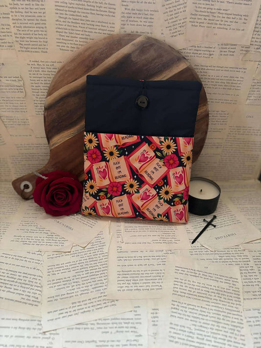 Standard book sleeve featuring red books, poppies and sunflowers on black fabric with graphic text "Fuck off I'm reading"